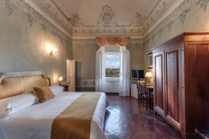 Schlafzimmer mit einem Bett, einem Schreibtisch und einem Fenster in der Unterkunft Hotel Palazzo di Valli in Siena