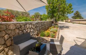 a stone wall with a bench and an umbrella at Apartmani Dino in Vrh