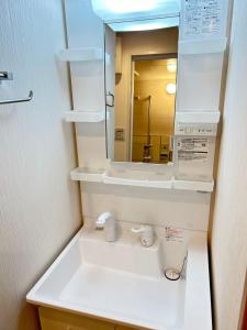 W łazience znajduje się biała umywalka i lustro. w obiekcie 大阪谷町橋の宿 w Osace