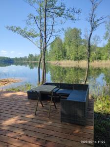 a picnic table and chairs on a deck next to a lake at Pelakys Glamping Lounge in Šlepečiai