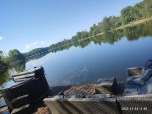 a view of a lake with two chairs on a dock at Pelakys Glamping Lounge in Šlepečiai