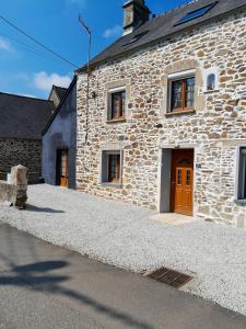 un edificio de piedra con una puerta marrón en una calle en Maison de 3 chambres avec jardin clos et wifi a Quettehou, en Quettehou