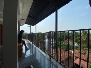 un uomo seduto su un balcone che guarda la vista di Luxe Inn a Kannur