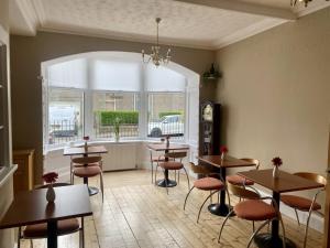 a restaurant with tables and chairs and a window at Lomond Guest House in Leven-Fife