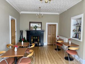 una sala da pranzo con tavoli, sedie e camino di Lomond Guest House a Leven-Fife