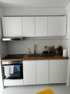 ジュピテルにあるOxygen studioの白いキャビネットとシンク付きのキッチン