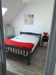 een slaapkamer met een bed met een rode deken bij pastelle in Contres