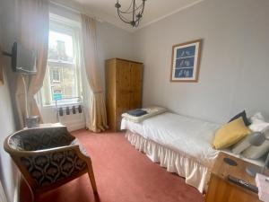 a bedroom with a bed and a chair and a window at Lomond Guest House in Leven-Fife