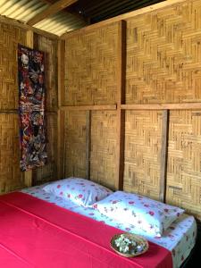 a bed in a room with a wooden wall at Homestay Bukit Lawang in Bukit Lawang