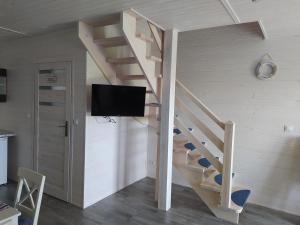 a living room with a wooden staircase with a flat screen tv at Domki Letniskowe Neptun II in Chłopy