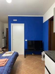 a blue room with a bed and a tv at A casa di Laura with pool and free bikes in Ronchi