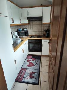 uma cozinha com armários brancos e um tapete no chão em Ferienwohnung Lay em Hirschaid