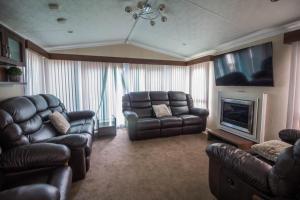 a living room with leather furniture and a couch and a television at Beautiful Caravan At Highfield Grange Holiday Park In Essex Ref 26687p in Clacton-on-Sea