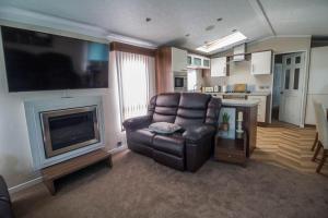 un soggiorno con poltrona in pelle e TV di Beautiful Caravan At Highfield Grange Holiday Park In Essex Ref 26687p a Clacton-on-Sea
