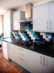 a kitchen with white cabinets and blue and white tiles at White House in Netherton