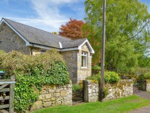uma casa de pedra com uma parede de pedra e uma cerca em Cairn Rigg em Rothbury