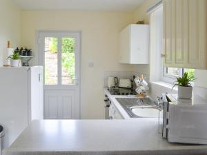 uma cozinha branca com um lavatório e um frigorífico em Cairn Rigg em Rothbury