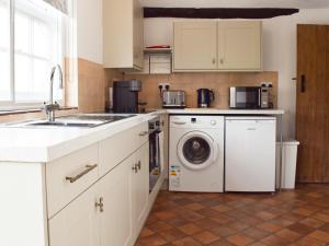 cocina con armarios blancos, lavadora y secadora en Hive Mews en Abingdon