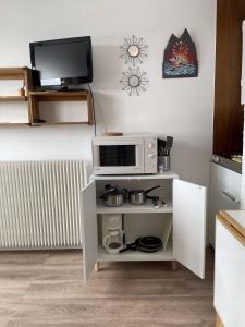 cocina con microondas y TV en la pared en Studio au coeur de la station des Menuires, en Les Menuires