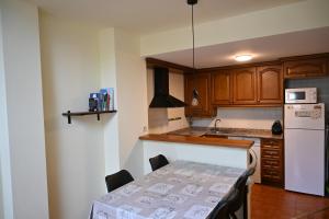 a kitchen with a table and a white refrigerator at Cal Roger D'Esterri in Esterri d'Àneu
