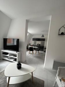 un soggiorno bianco con tavolo e TV di Expérience Malouine - Appt T3-Coeur de Malo-Plage a Dunkerque