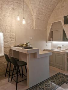 a kitchen with a counter and a bar with two stools at A casòdd' - Luxury Suite in Ceglie Messapica