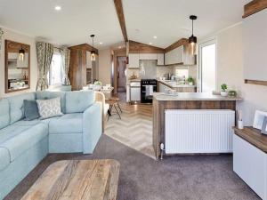 a living room with a blue couch and a kitchen at Stunning Caravan With Decking At Azure Seas In Suffolk Ref 32055az in Lowestoft