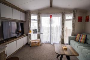 a living room with a couch and a table at Stunning Caravan With Decking At Azure Seas In Suffolk Ref 32055az in Lowestoft