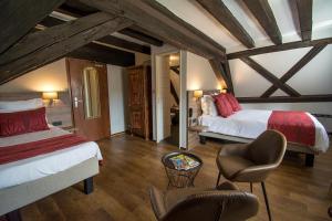 a bedroom with two beds and a chair in a room at Hôtel De La Couronne in Riquewihr