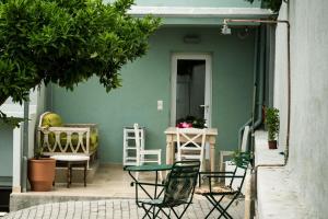 eine Terrasse mit Stühlen, einem Tisch und einer grünen Wand in der Unterkunft casa zervos - Abode of Light in Loutraki