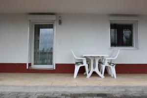 une table et des chaises blanches devant un bâtiment dans l'établissement Bodensee Pension, à Überlingen