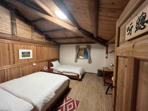 two beds in a room with wooden walls at Horn Seaside Homestay in Nangan