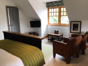 a living room with a couch and chairs and a television at Sutherlands Guest House in Kingussie