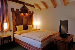 Schlafzimmer mit einem Bett mit einem Kopfteil aus Holz und einem TV in der Unterkunft Chez Jean in Saverne