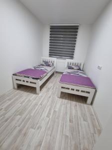 ヤゴディナにあるSilver city 1の白い壁とウッドフロアの客室で、ベッド2台が備わります。