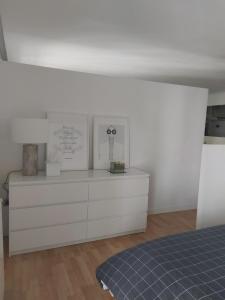a white bedroom with a bed and a dresser at Loft luminoso y céntrico in Zaragoza