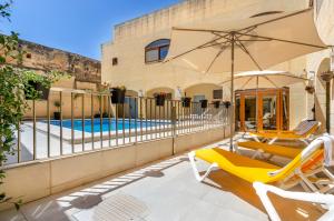 a patio with two chairs and an umbrella and a pool at Country Stays Hostel in Sannat