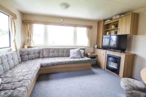 a living room with a couch and a television at 8 Berth Caravan At Highfield Grange In Essex Ref 26267e in Clacton-on-Sea