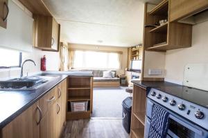 a small kitchen with a sink and a stove at 8 Berth Caravan At Highfield Grange In Essex Ref 26267e in Clacton-on-Sea
