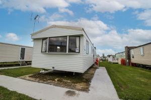 a small white tiny house parked in a yard at 8 Berth Caravan At Highfield Grange In Essex Ref 26267e in Clacton-on-Sea