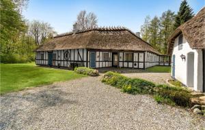 een oud huis met een rieten dak en een grindoprit bij Lovely Home In Glamsbjerg With Kitchen in Glamsbjerg