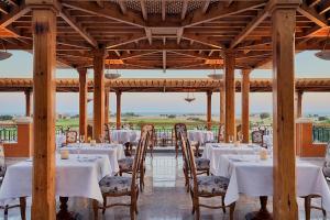 a dining room with white tables and chairs at The Cascades Golf Resort, Spa & Thalasso in Hurghada
