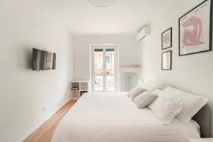 a white bedroom with a large bed with white sheets and pillows at Trastevere Boutique Apartment in Rome