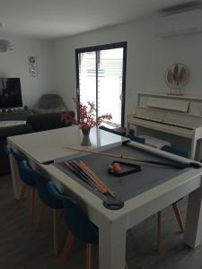 a ping pong table in a living room with a piano at Location Saisonnière Villa in Uzès