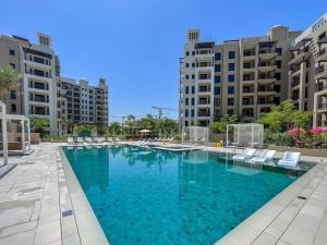 a large swimming pool with white chairs and buildings at Vogue Jumeirah Living - Near Burj Al Arab & Beach in Dubai
