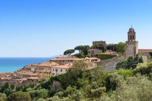 a village on top of a hill with a clock tower at Appartamento Bell’Umore in Castiglione della Pescaia