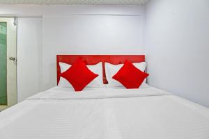 een wit bed met rode kussens erop bij OYO Flagship Hotel Happiness Inn Near Tdi Mall in New Delhi