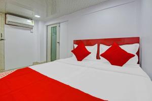 een slaapkamer met een wit bed met rode kussens bij OYO Flagship Hotel Happiness Inn Near Tdi Mall in New Delhi