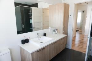 y baño con lavabo blanco y espejo. en Le Citadin - Maison neuve moderne & ensoleillée, en Quebec