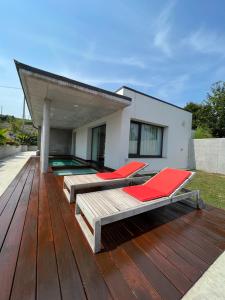 eine Terrasse mit roten Stühlen und ein Haus in der Unterkunft Villas Vairocana in Santillana del Mar